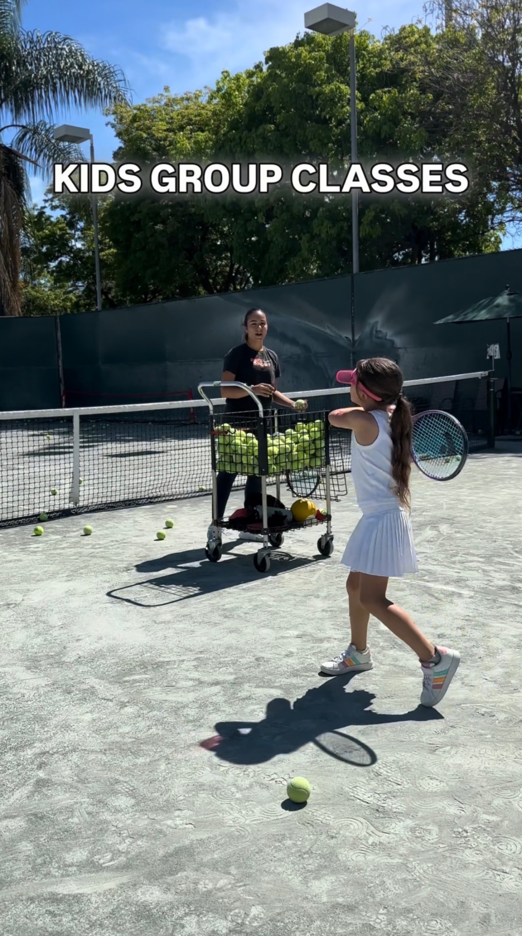 Coach feeding balls during kids group class