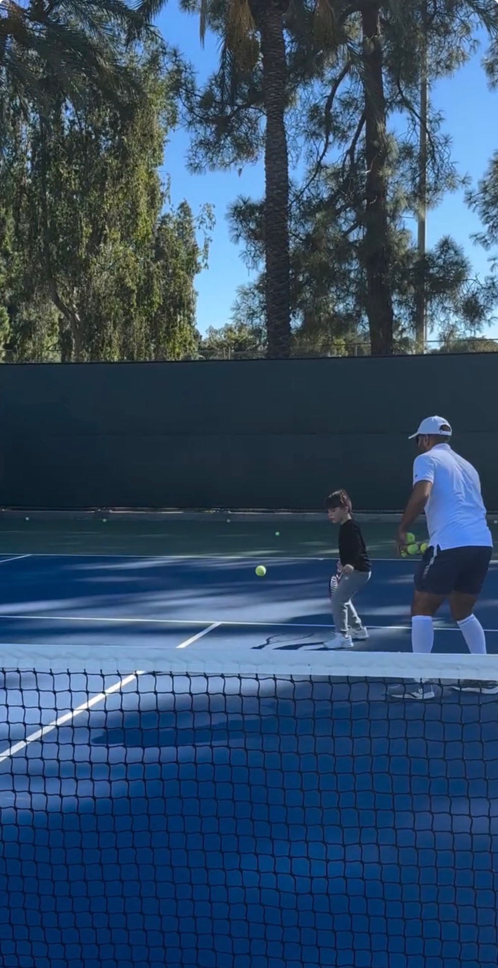 Coach feeding balls to a young student